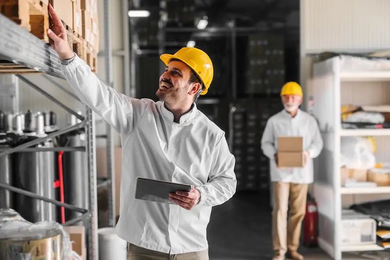 Trabajador en un almacén revisando inventarios con una tableta, optimizando el control de existencias mediante tecnología moderna.