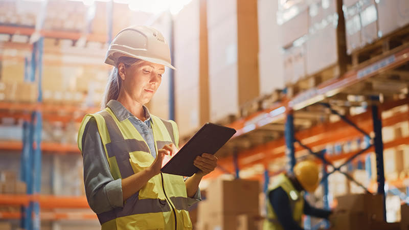 Employee using warehouse inventory software on a tablet for stock management