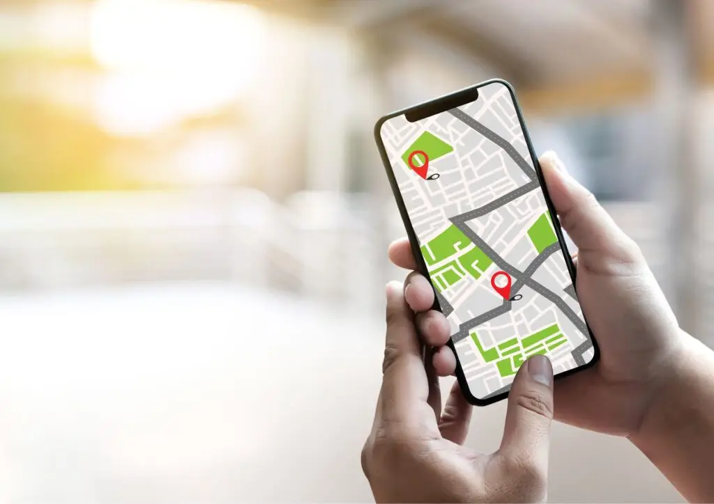 Persona usando una aplicación de seguimiento GPS en el móvil para localizar y gestionar vehículos de la flota en tiempo real.