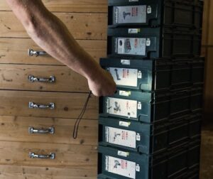 Mano de un trabajador escaneando etiquetas QR en un sistema de almacenamiento de cajones para controlar herramientas y materiales mediante Timly.