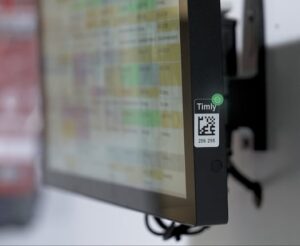 Etiqueta QR de Timly adherida a la pantalla de un dispositivo electrónico para facilitar su identificación y gestión digital.