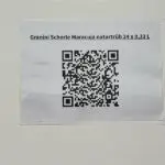 Código QR impreso en una hoja, colocado en la pared de la IHK Hannover para la gestión digital de activos.