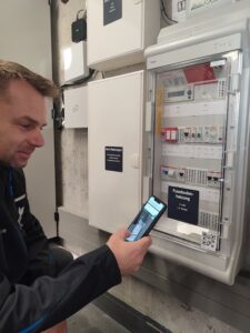 Empleado de Hafen & Hof escaneando un código QR de Timly en un panel técnico para gestionar el inventario digitalmente.