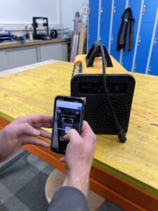 Empleado escaneando el código QR Timly de una herramienta con su smartphone para gestionar el inventario.