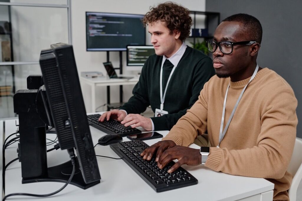 Equipo de TI trabajando con ordenadores en una oficina, ilustrando la gestión de servicios de TI según las mejores prácticas ITIL.