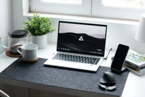 Escritorio de oficina con portátil, smartphone y accesorios organizados para la gestión de activos de TI.