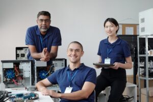 Des employés IT illustrent le guide explicatif de Timly, le logiciel de gestion de parc informatique. Ils sont souriants et entourés d'ordinateurs.