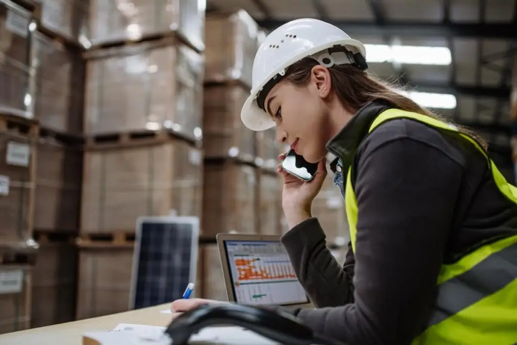 Une employée au téléphone, dans un entrepôt, en train de passer une commande, pour illustrer un article de blog sur la gestion des stocks juste-à-temps
